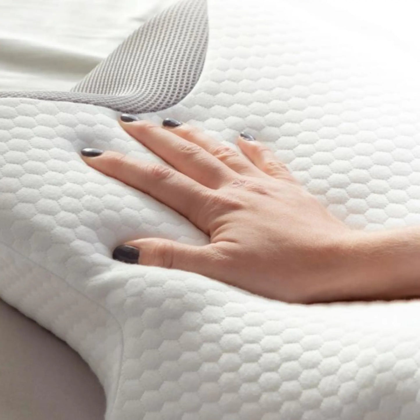 Hand pressing on NEURA ergonomic memory foam pillow, showcasing its soft and supportive texture.