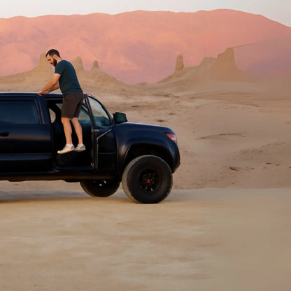 Man using SKYSTEP™ foldable car door step on a black SUV in a desert landscape.